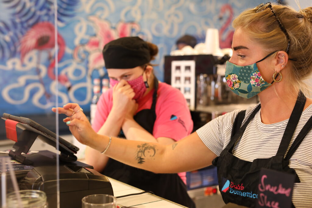 Two women wearing masks and serving customers at Café Domenica during Covid-19