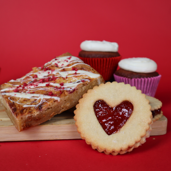 A variety of backed good set upon a red backgrouns. These include Raspberry Blondies, Red Velvet Cupcakes and Homemade ‘Jammy Dodgers’ - all of which look delicious!