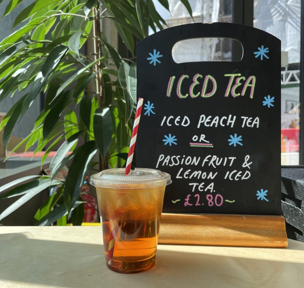 an iced tea its in the sunshine next to a sign