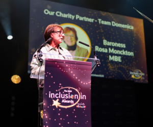 Baroness Rosa Monckton MBE stands behind a podium whilst speaking at WiHTL & DiR's Inclusion in Awards