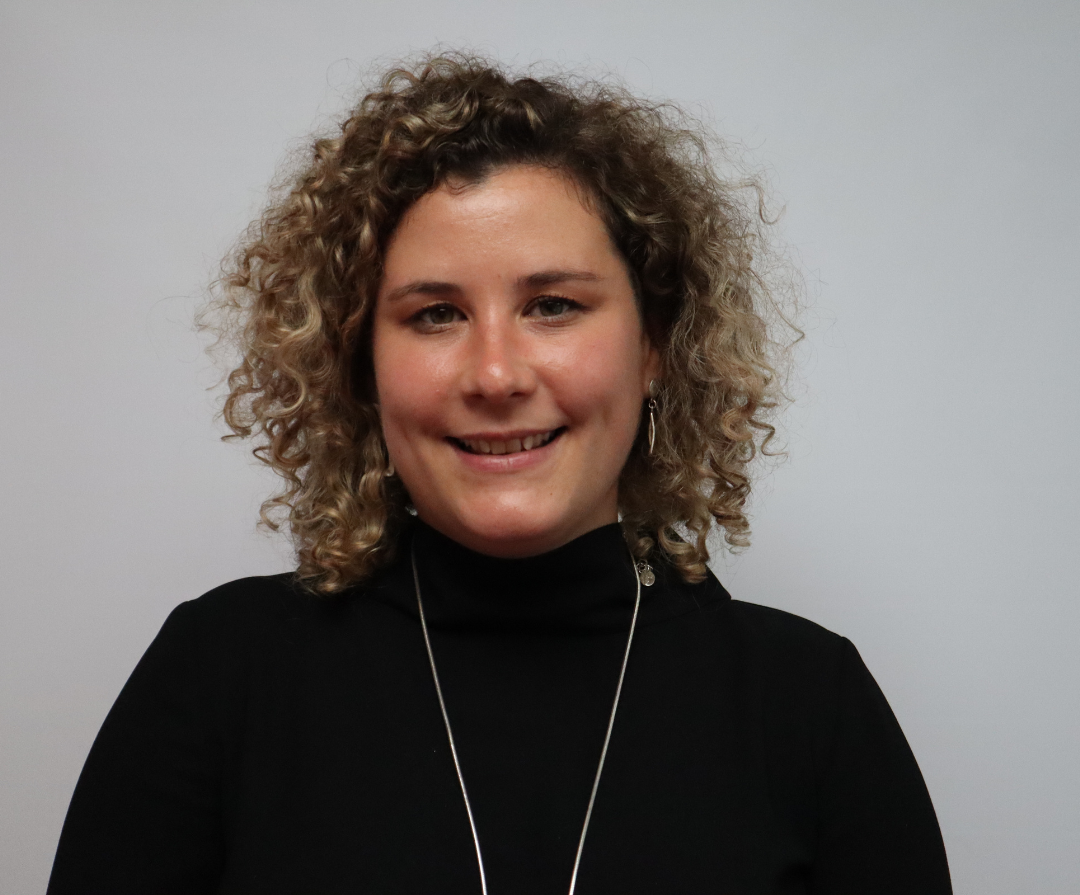 A headshot of Kate Payne. She is white and has dark blonde curly hair.