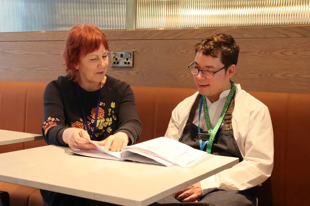 A Team Domenica candidate sits with staff talking about their paid job