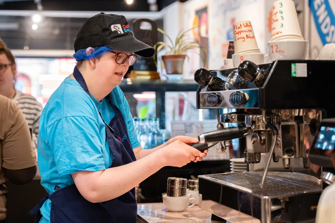 A Team Domenica candidate training on the coffee machine in one of the cafes
