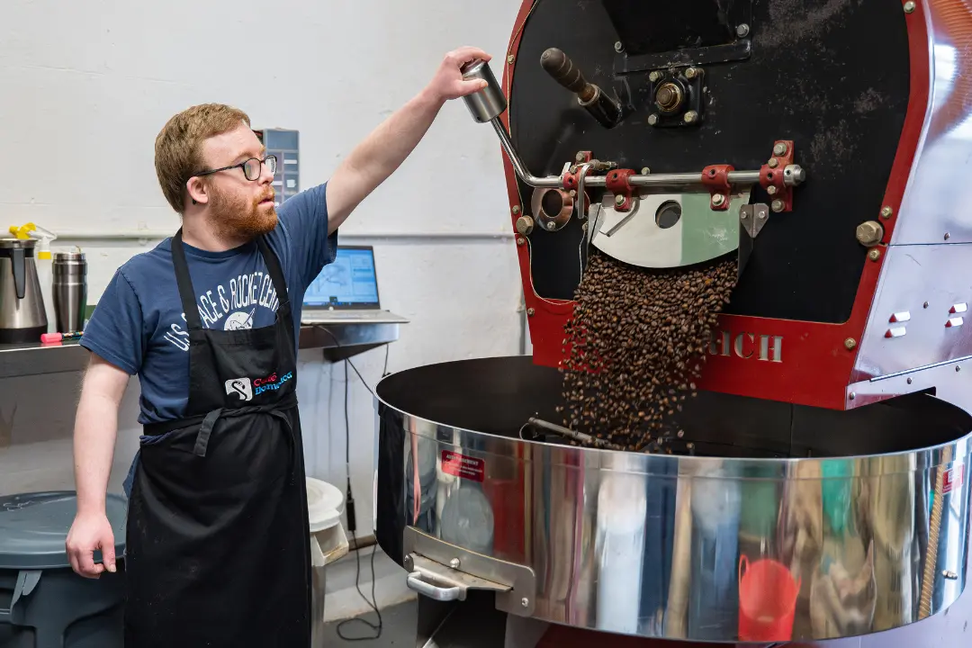 A Team Domenica candidate roasts coffee ready to be packaged and sold