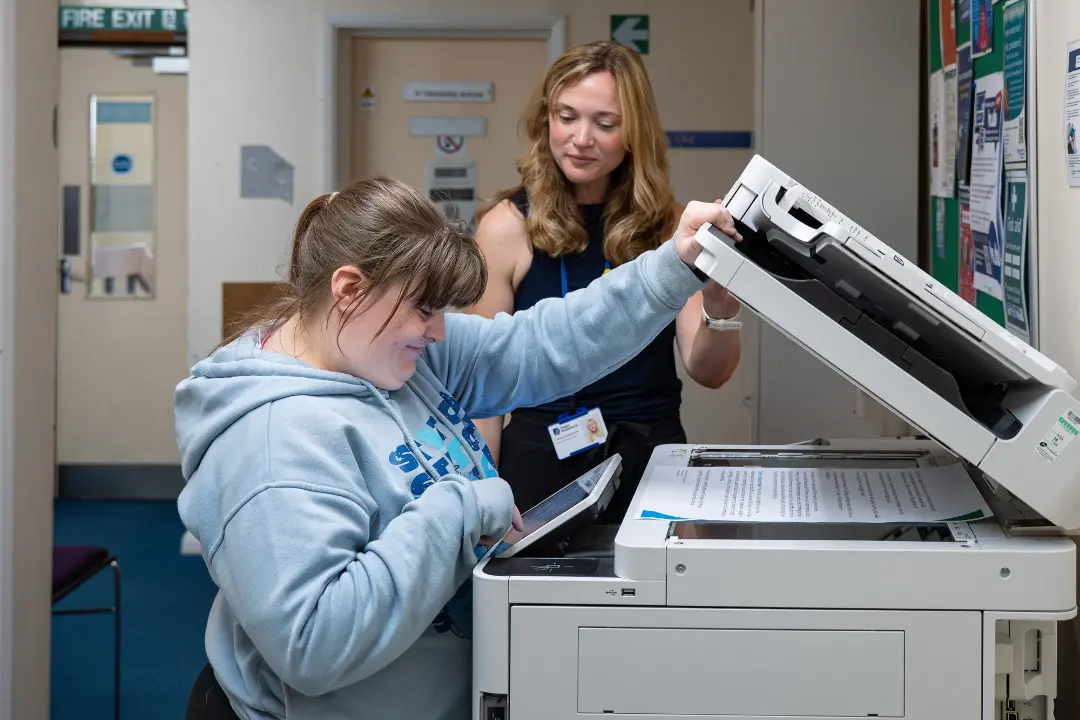 A Team Domenica candidate is supported by a Job Coach on their work placement doing admin