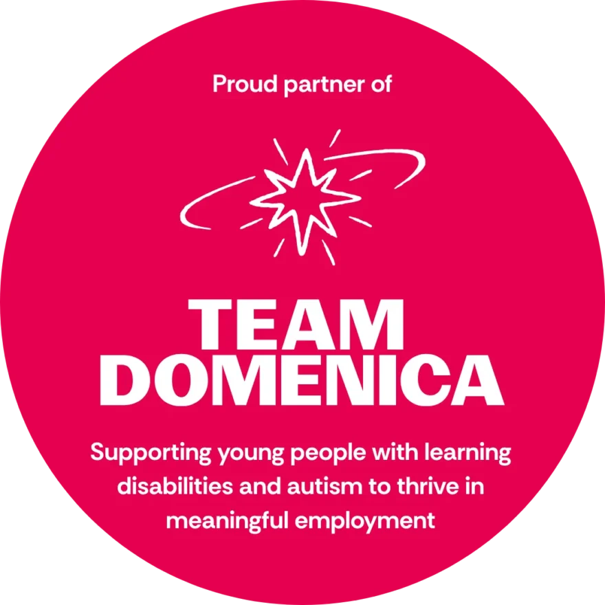 A pink circular badge with the words: Proud partner of Team Domenica. Supporting young people with learning disabilities and autism to thrive in meaningful employment