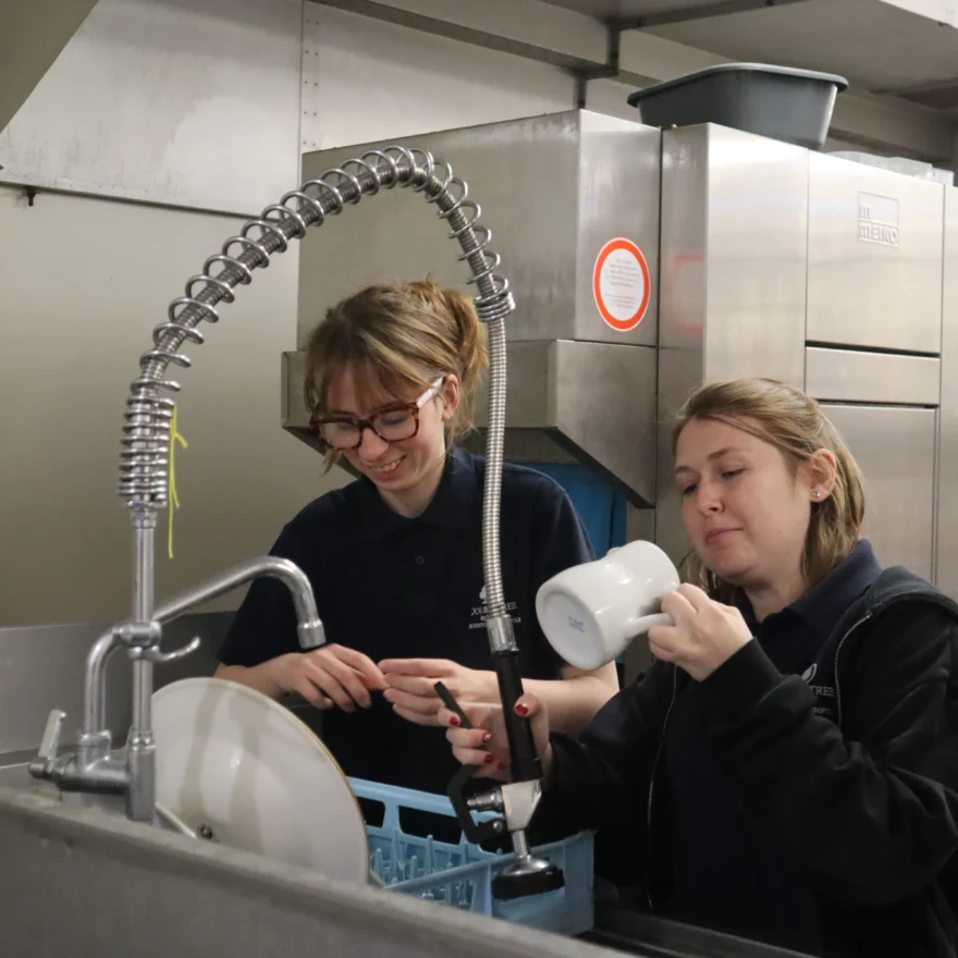 Two women dressing up in commercial kitchen